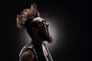 Profile shot of an angry punk rocker shouting on dark background